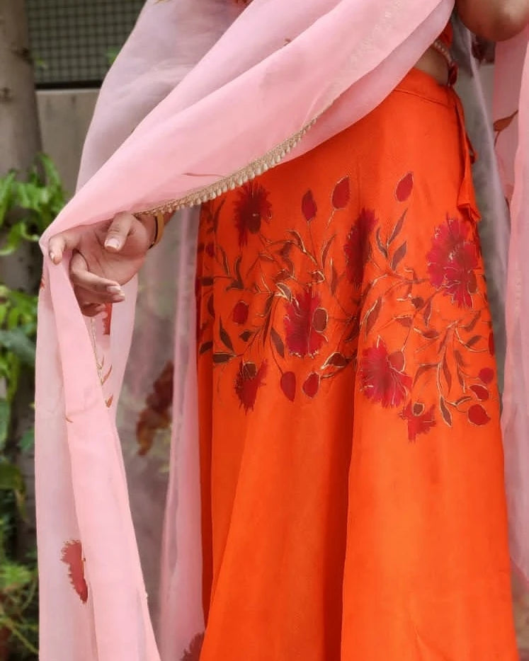 Orange garment with floral embroidery held by a person wearing a pink dupatta.