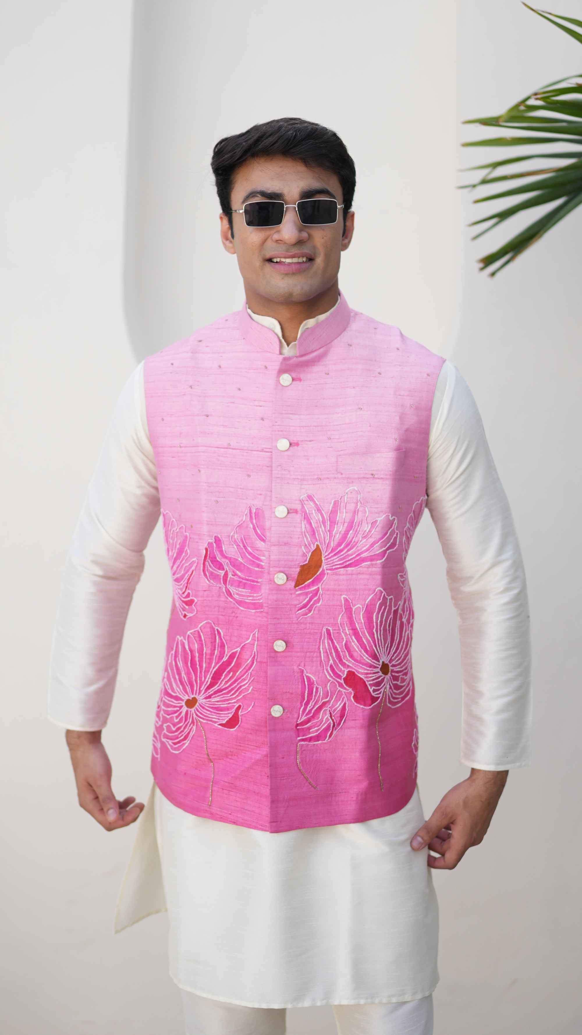 Person wearing a traditional hand painted outfit with a pink nehru jacket and white pants, standing on a light-colored floor.