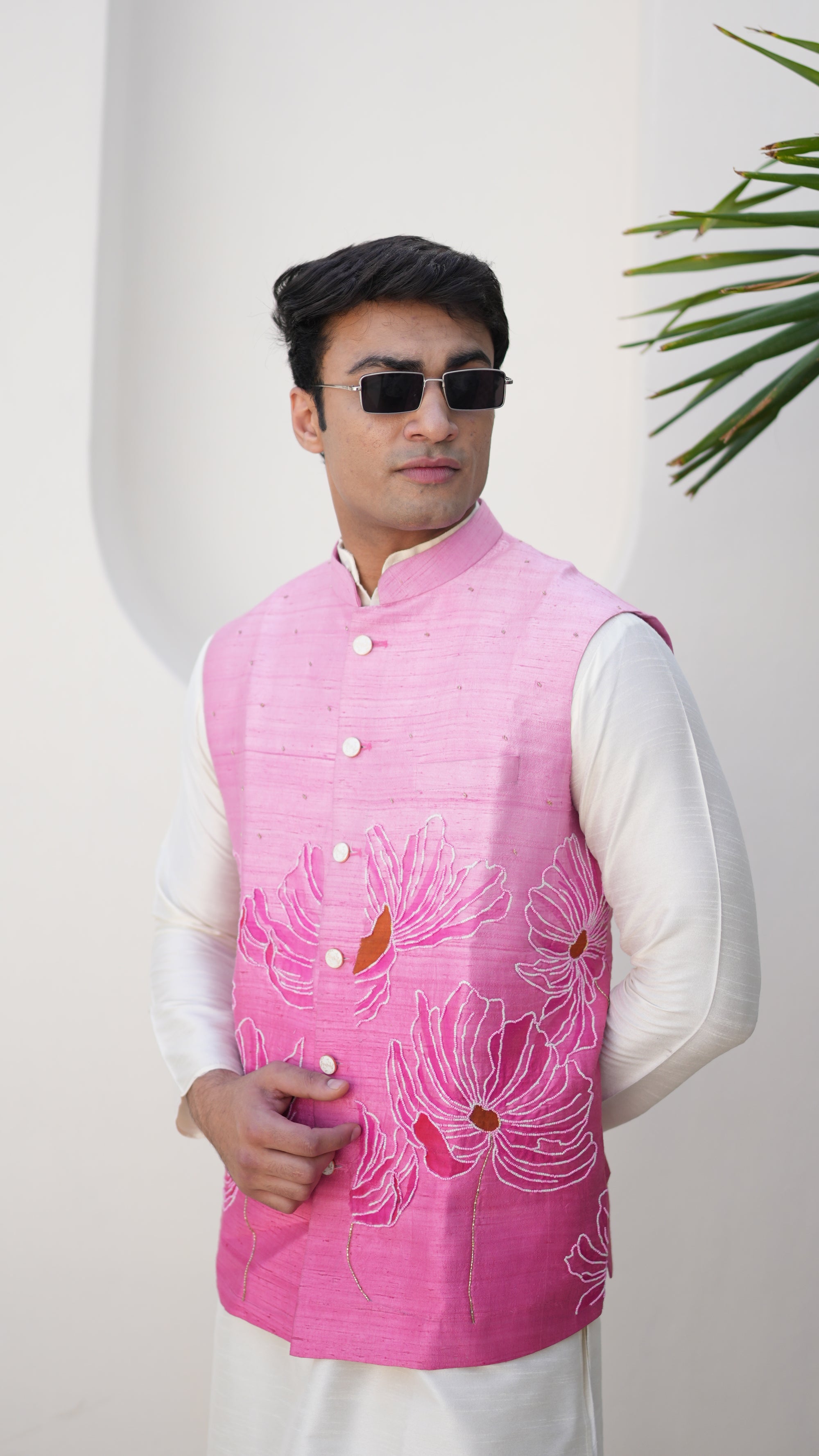 Person wearing a traditional hand painted outfit with a pink nehru jacket and white pants, standing on a light-colored floor.