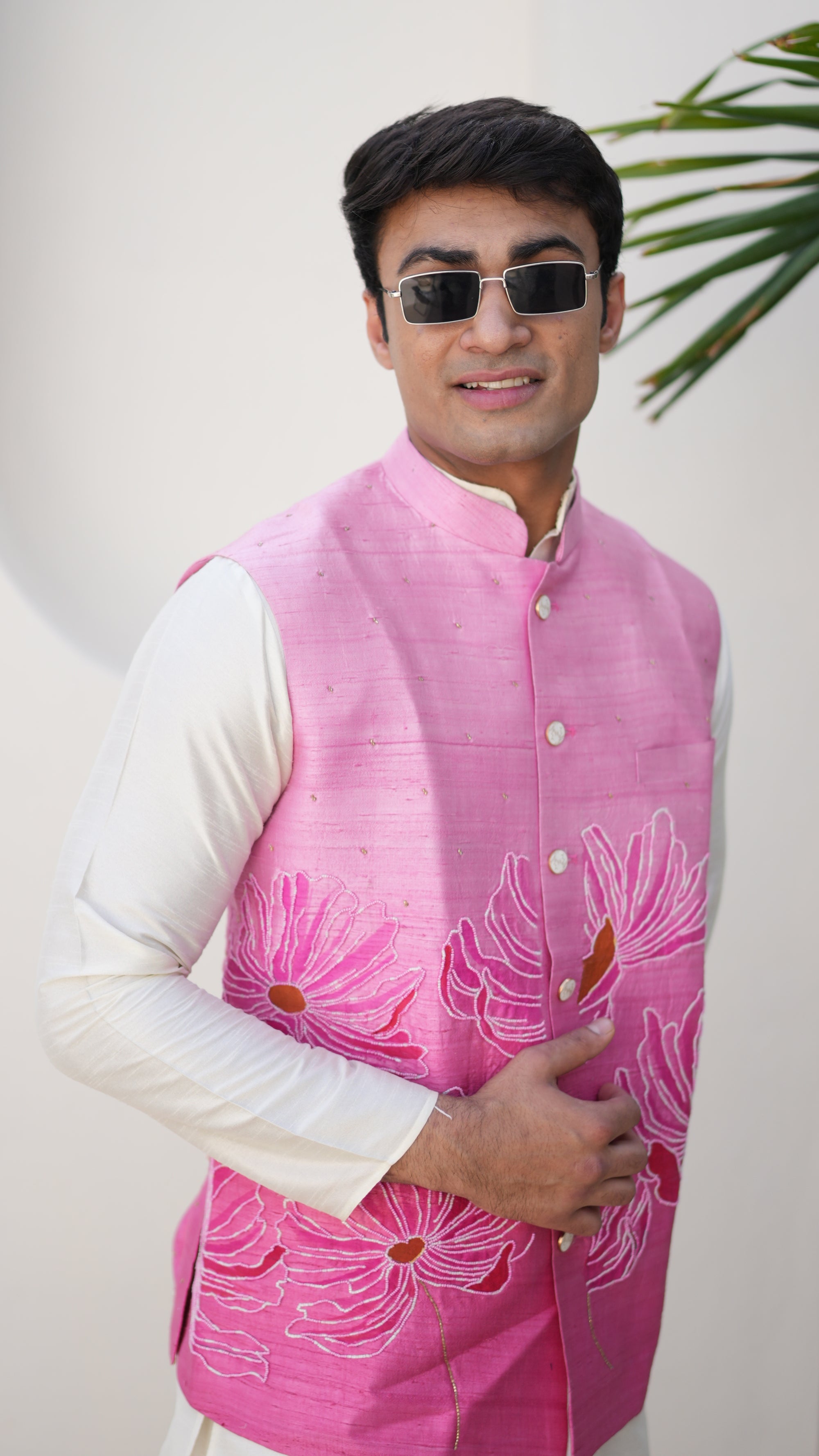 Person wearing a traditional hand painted outfit with a pink nehru jacket and white pants, standing on a light-colored floor.