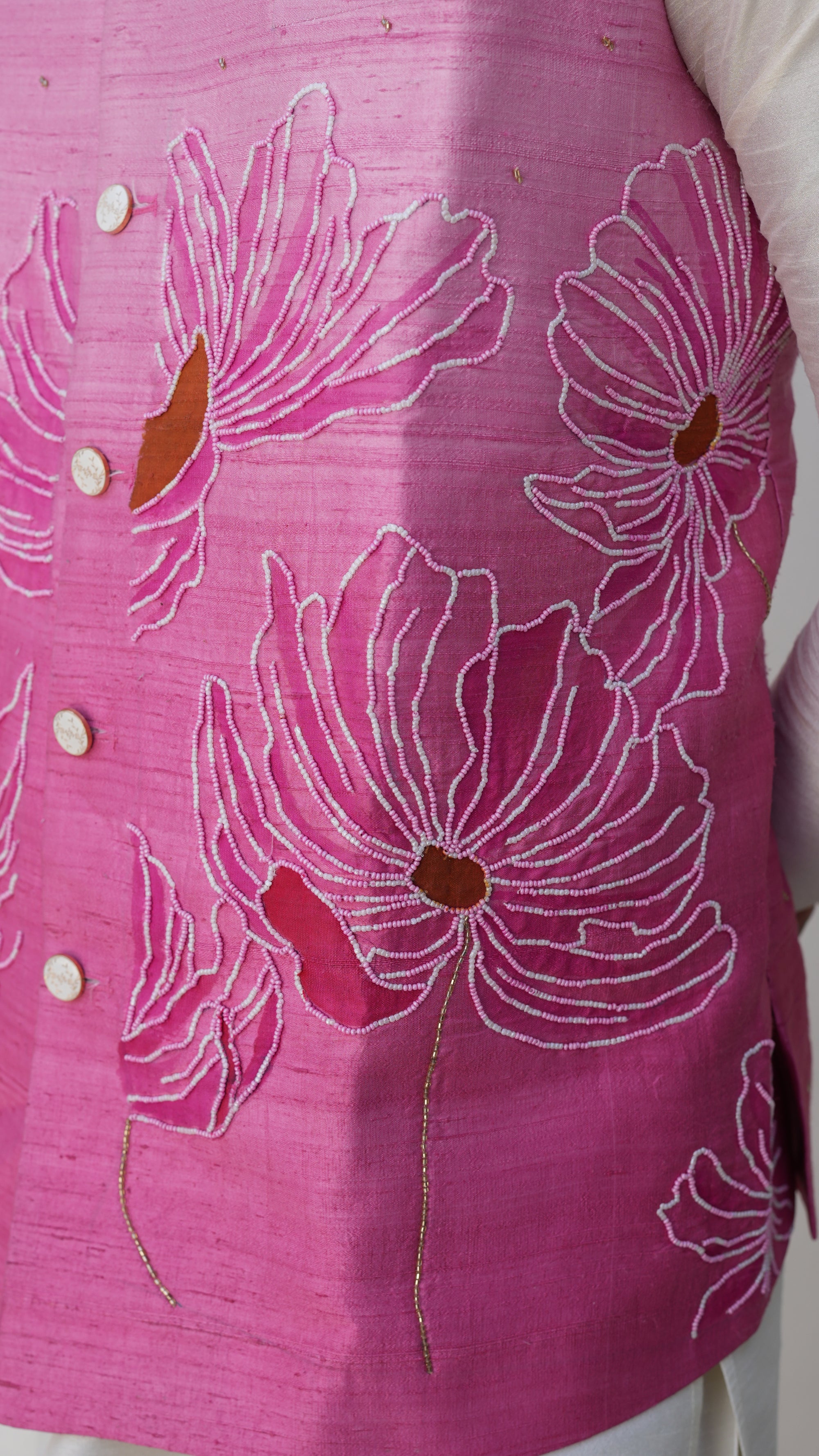 Pink fabric with hand painted white floral patterns and buttons on a white background