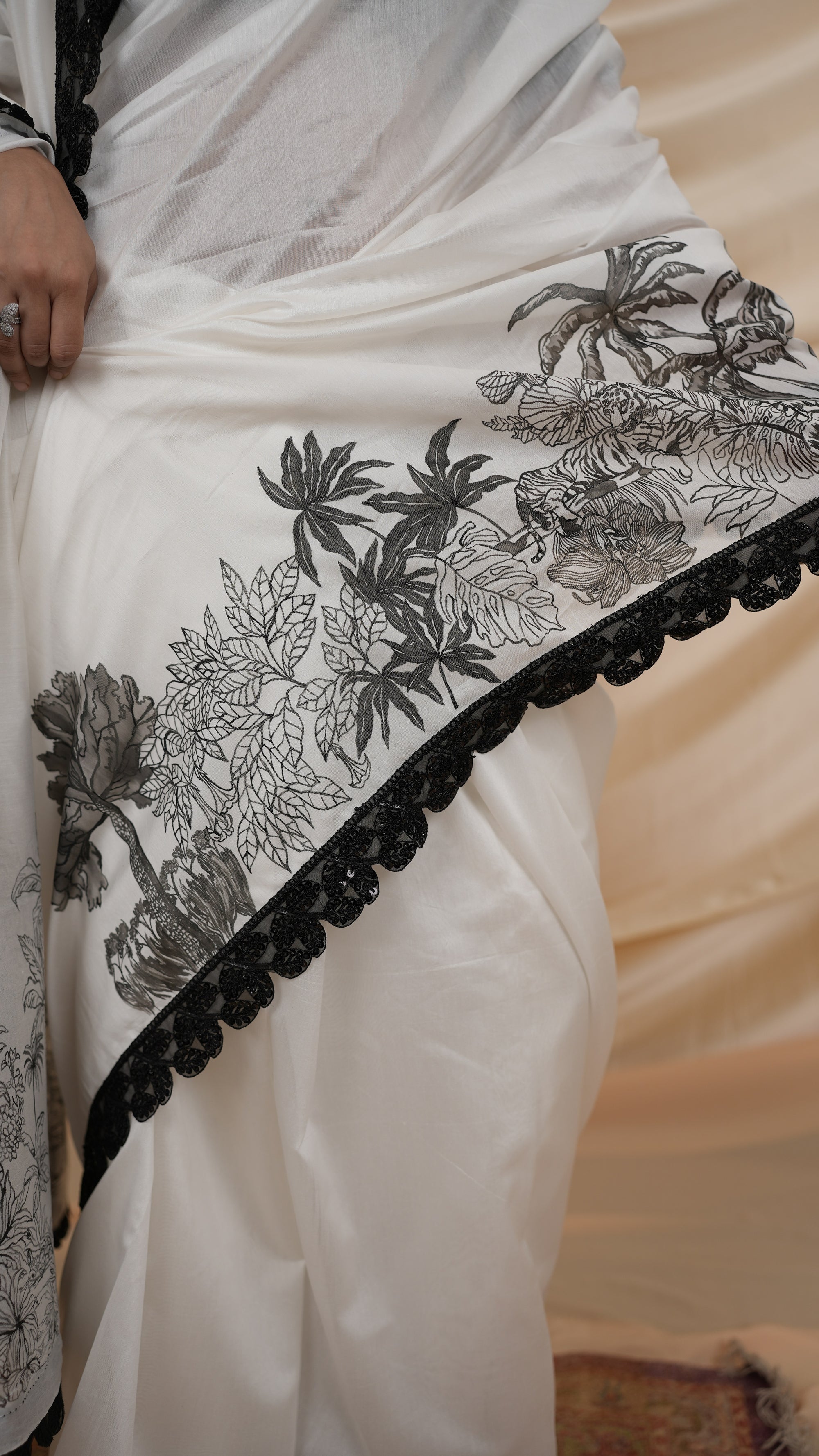 White saree with black hand painted floral and border on a neutral background