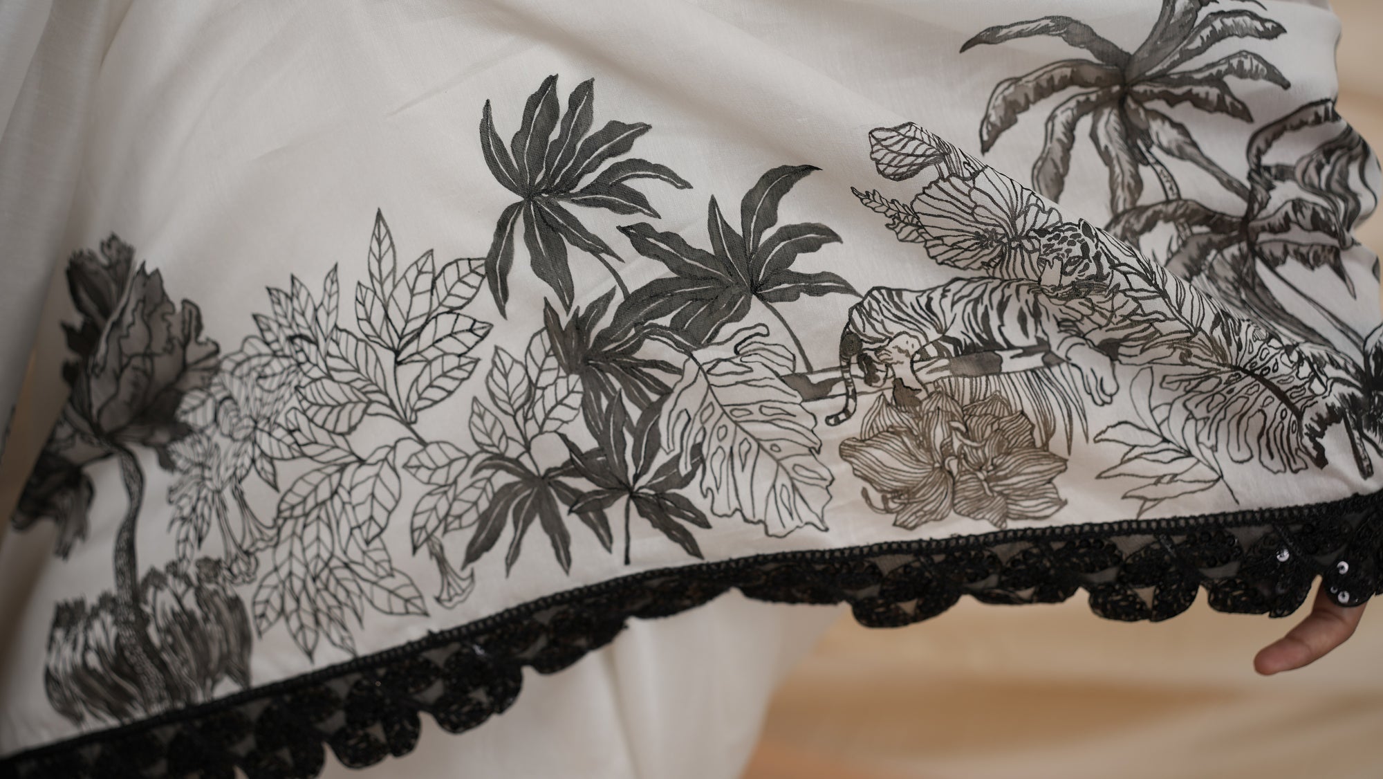 Close-up of a fabric with black floral embroidery on a white background