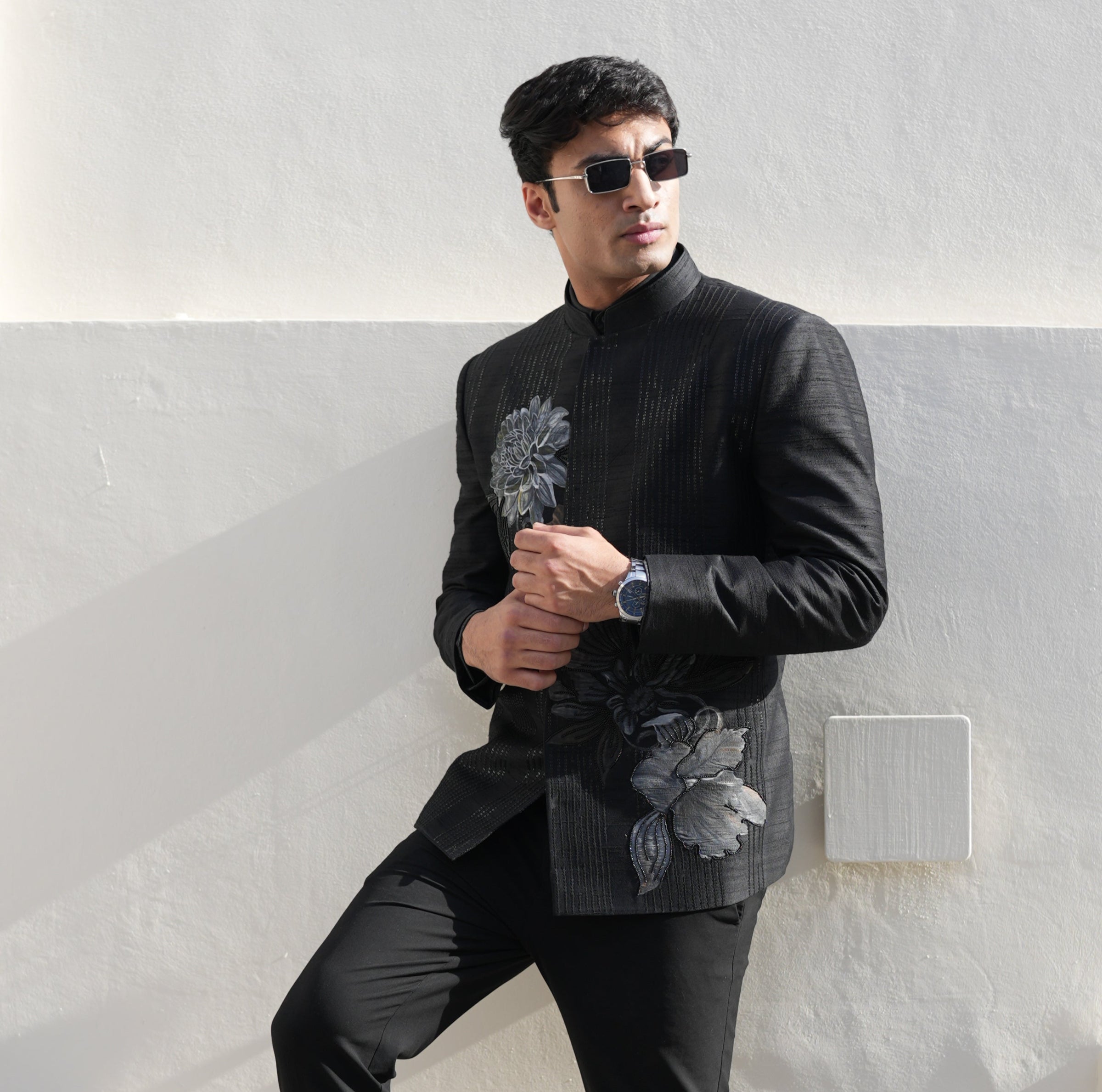 Person wearing a black suit with floral details on a white background