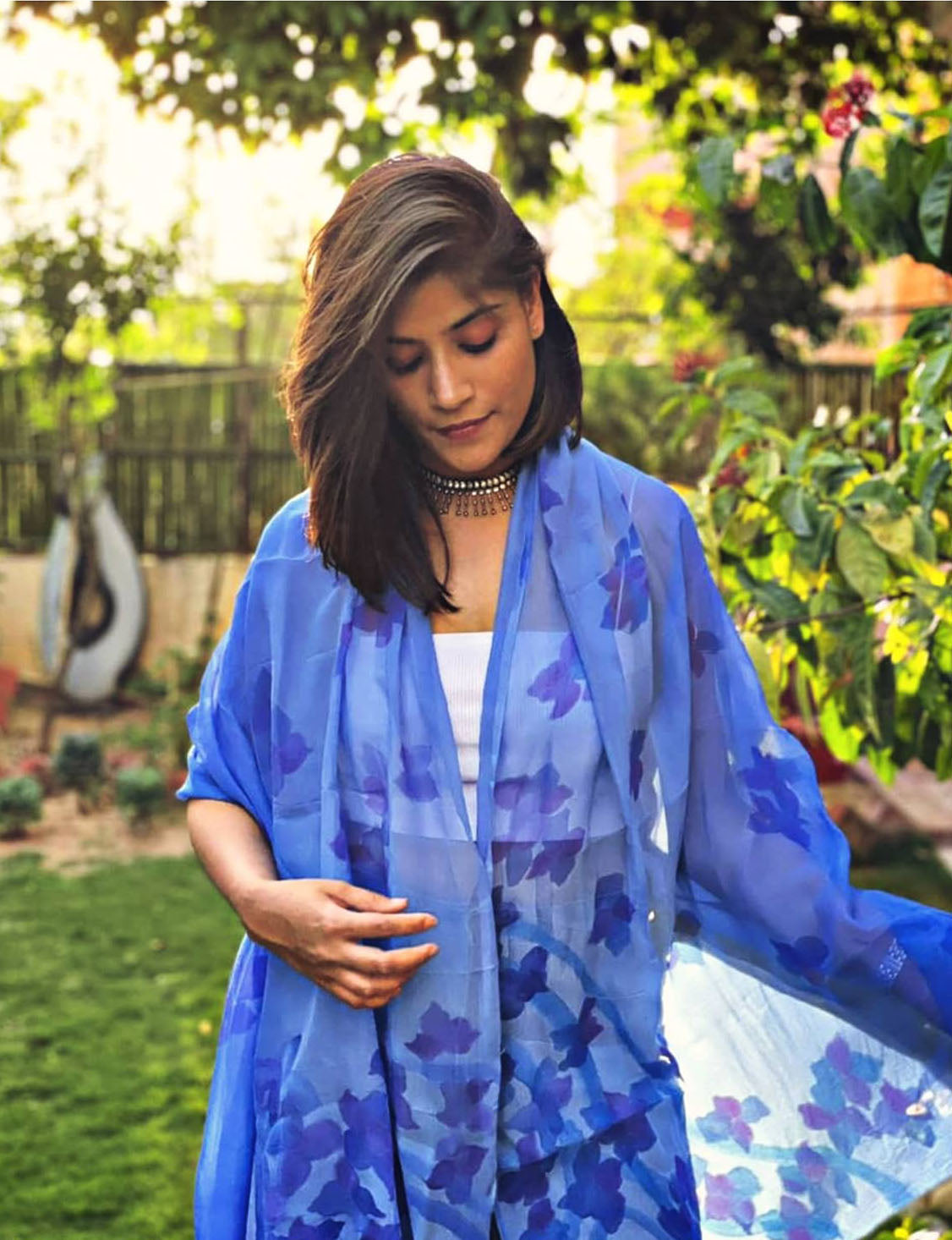 Woman wearing a blue hand painted floral stole in a garden setting