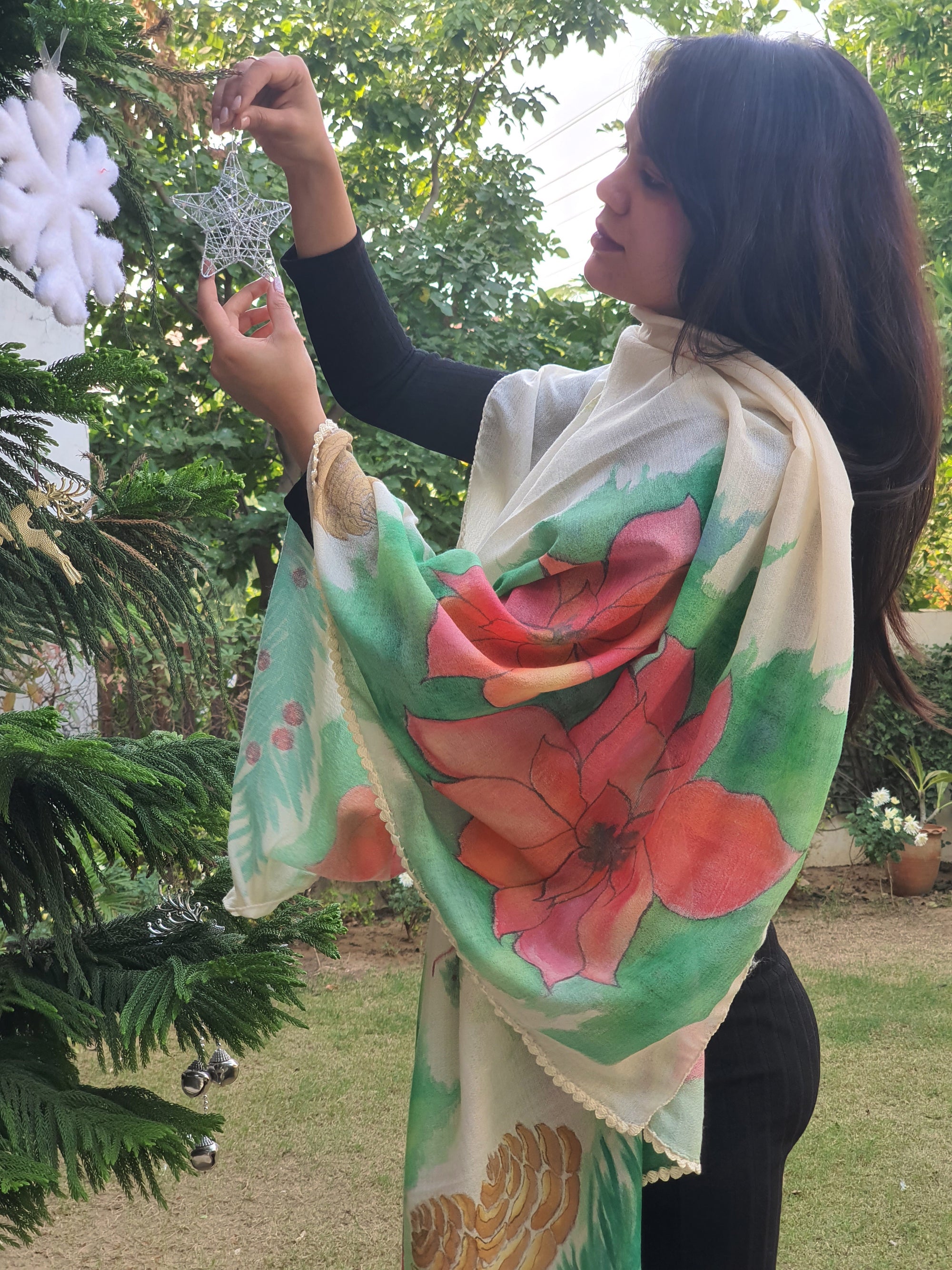 Person wearing a hand painted floral scarf with red flowers and green leaves, standing outdoors.