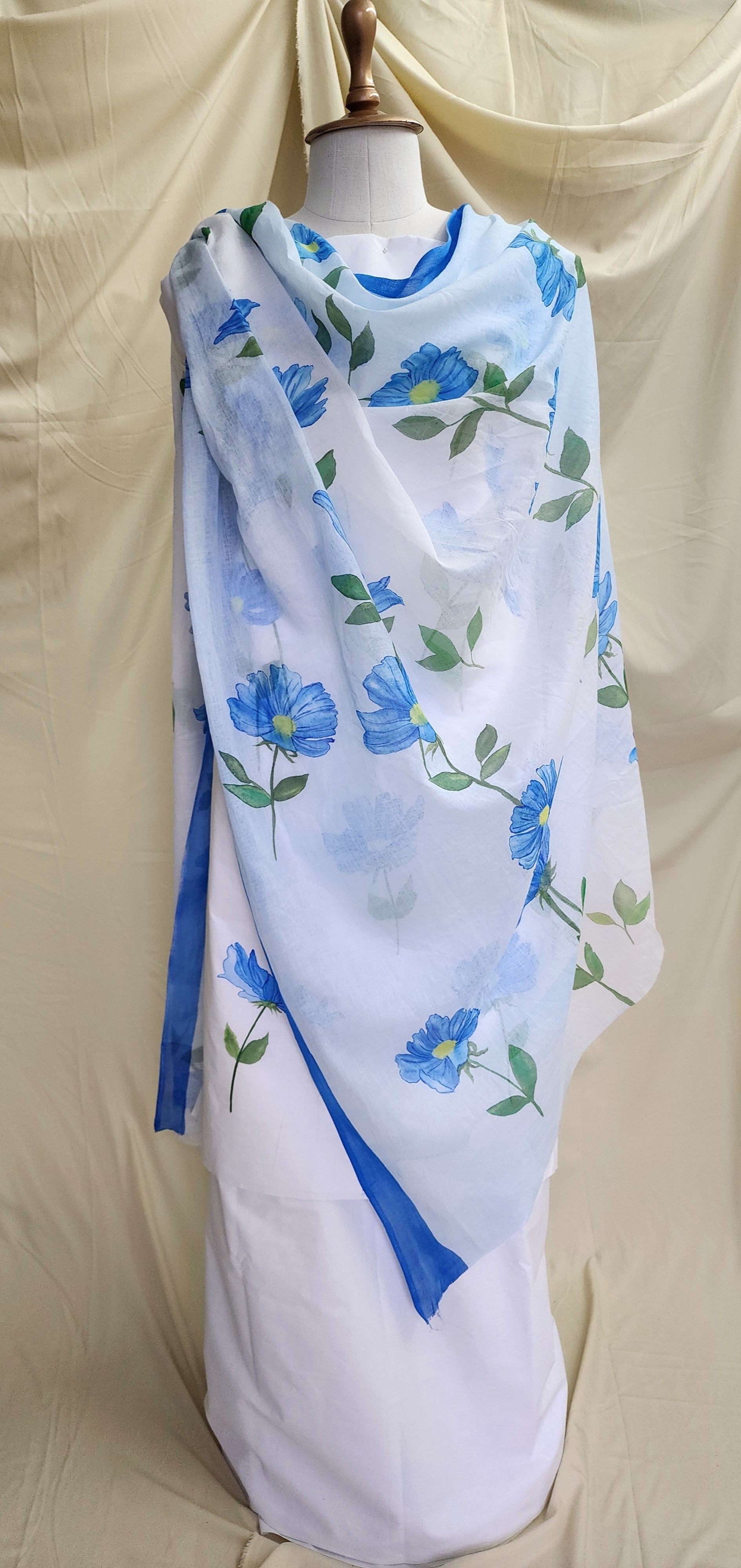 White suit set with blue floral patterns on a mannequin against a beige background