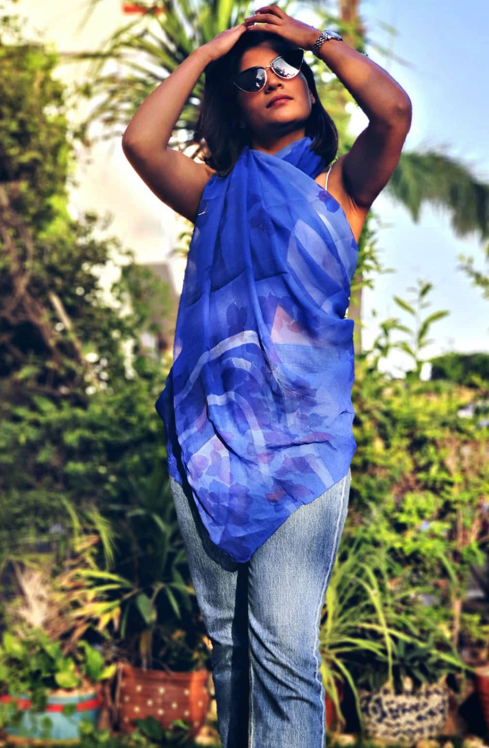 Woman wearing a blue hand painted floral stole in a garden setting