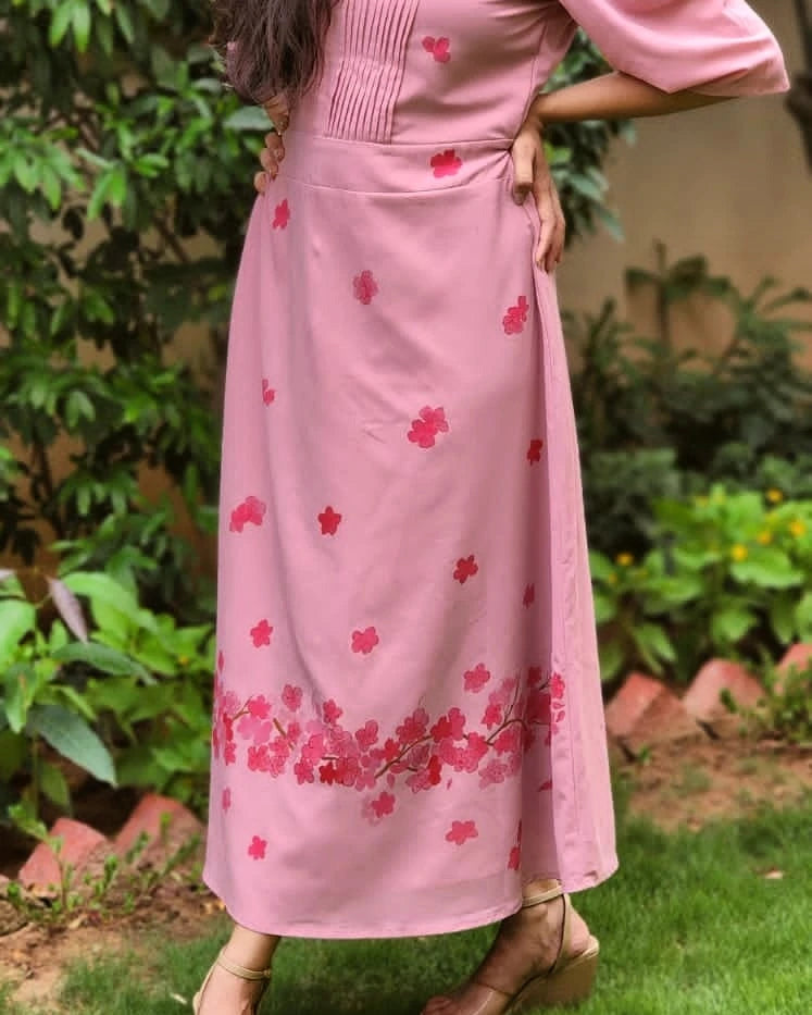 Person wearing a pink dress with red floral patterns in an outdoor setting.