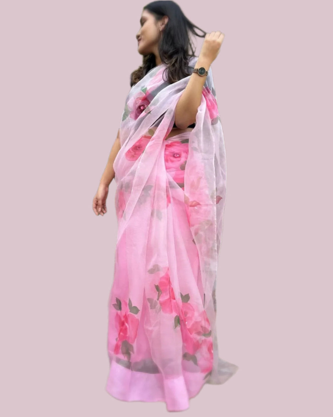 Woman wearing a pink saree with floral patterns.