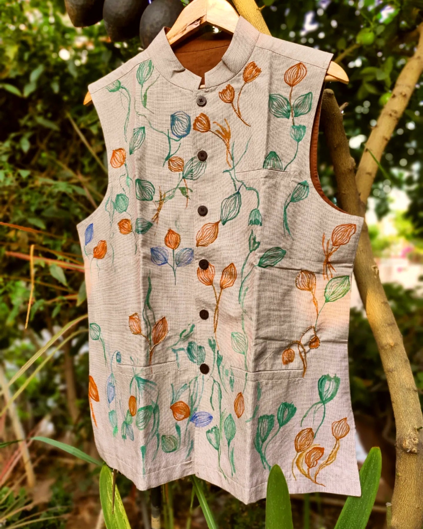 Hand painted nehru jacket with floral patterns hanging against a natural background