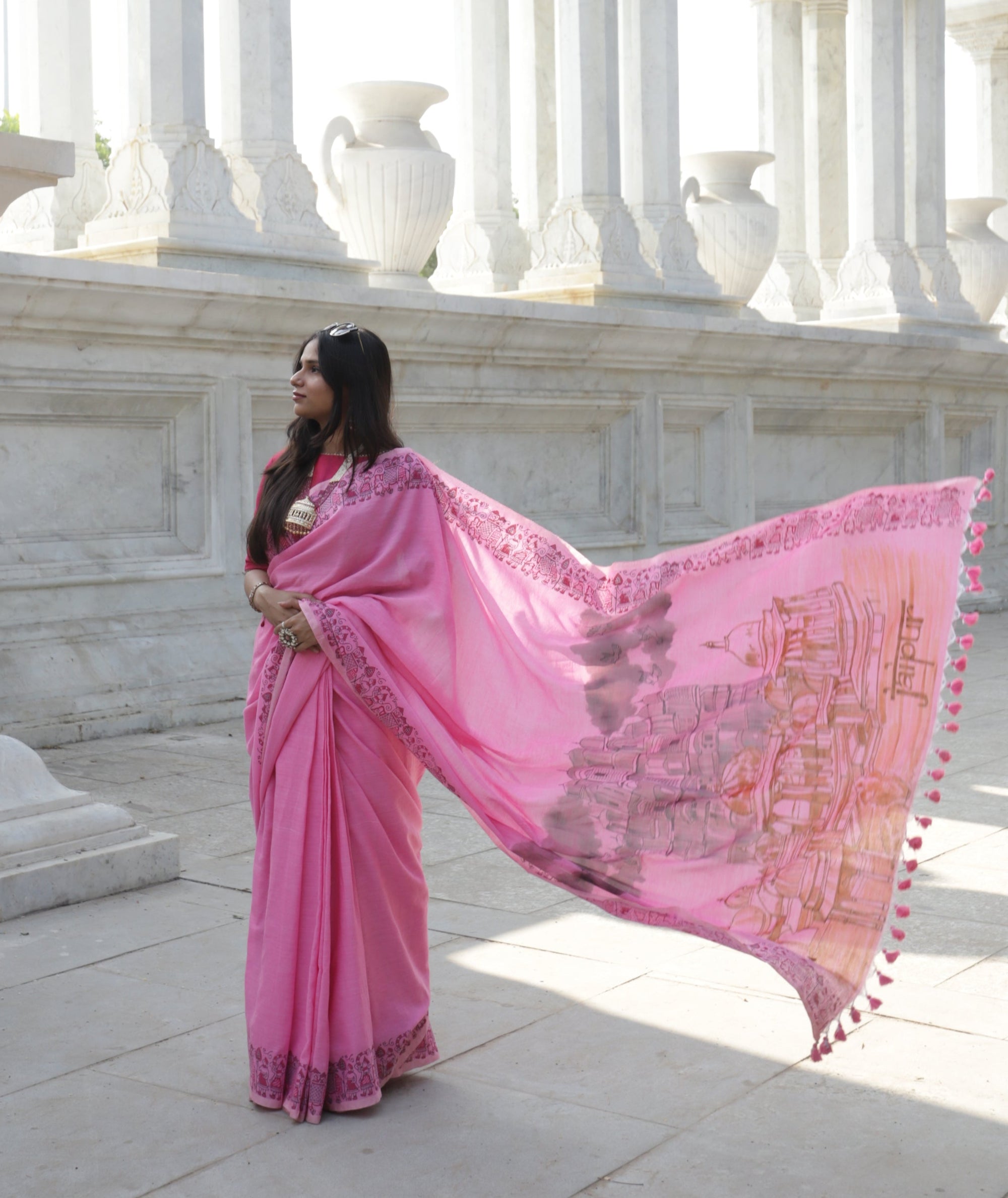 Woman in a pink sari standing in front of a white marble structure in Jaipur