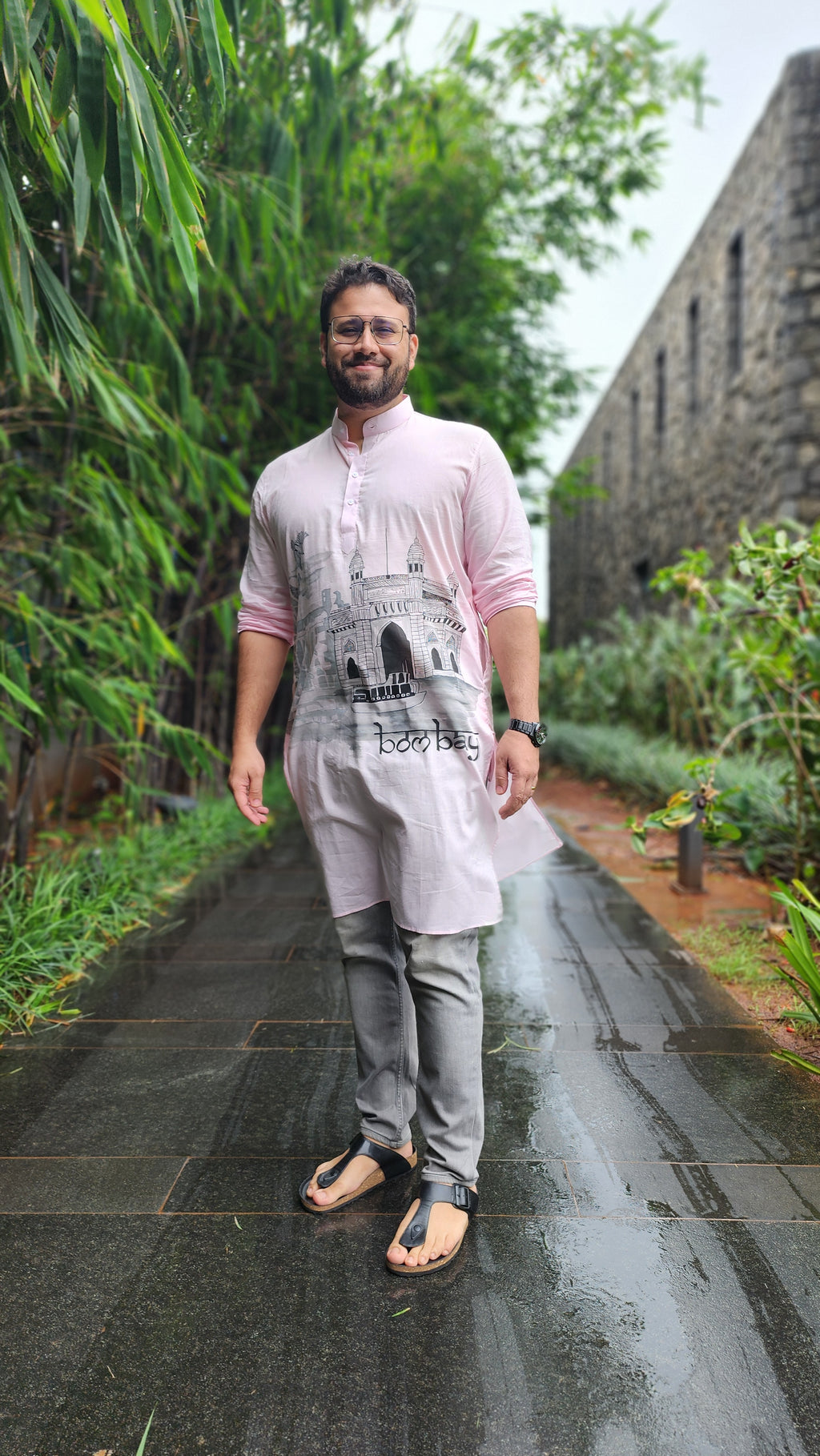 Person standing on a reflective surface with greenery in the background