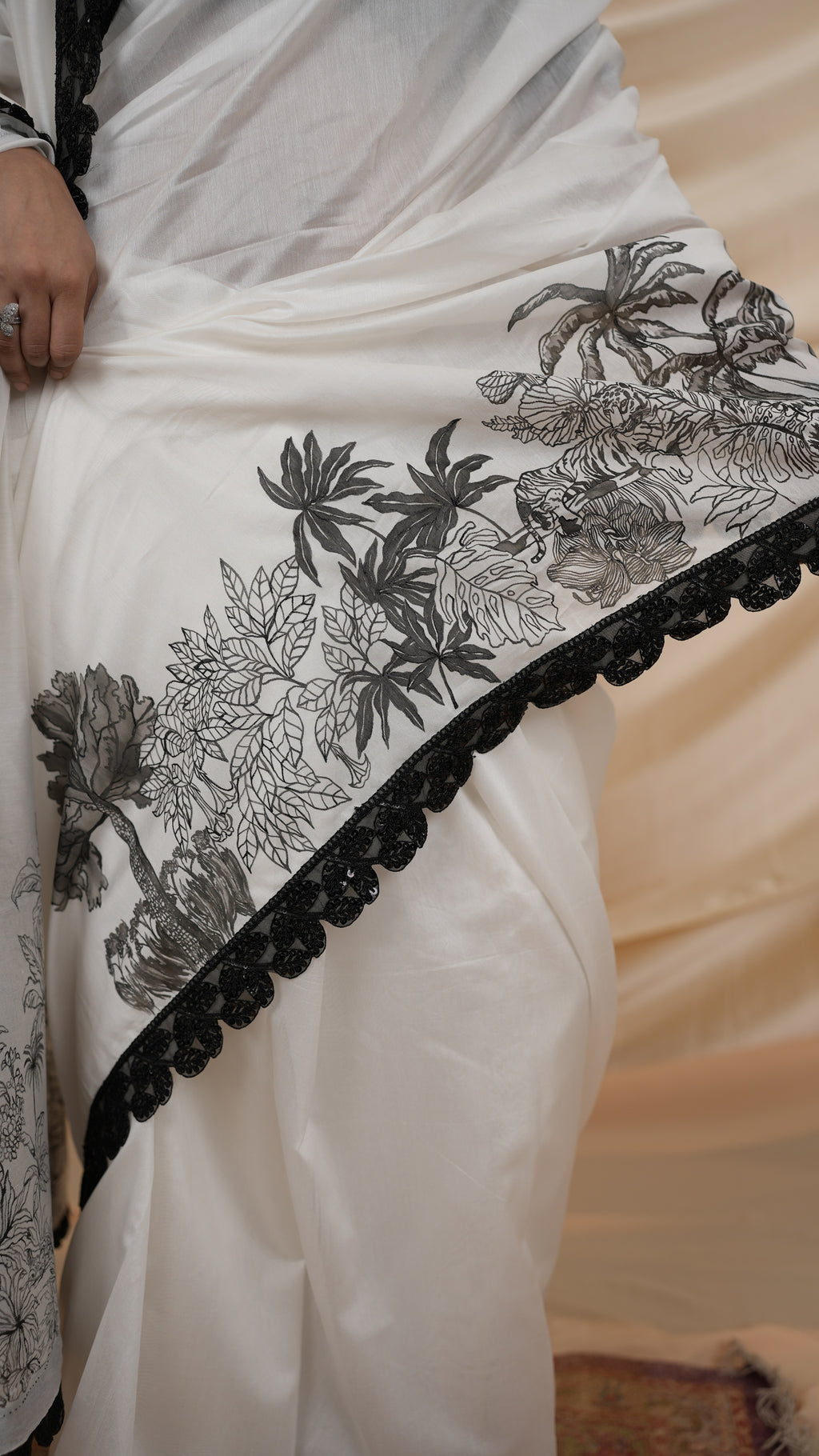 White saree with black hand painted floral and border on a neutral background