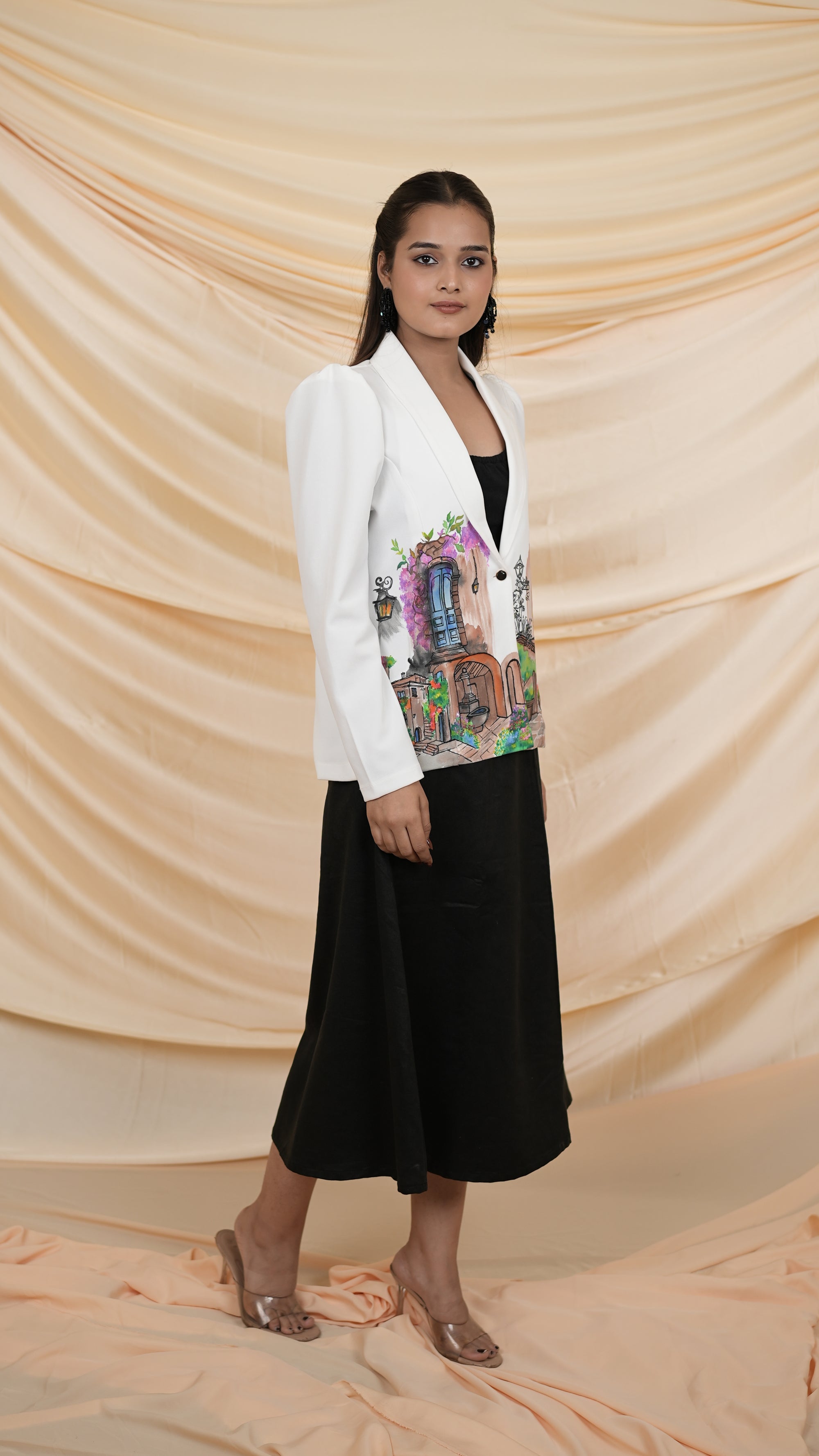 Women wearing a white blazer with a colorful hand painted design and black skirt.