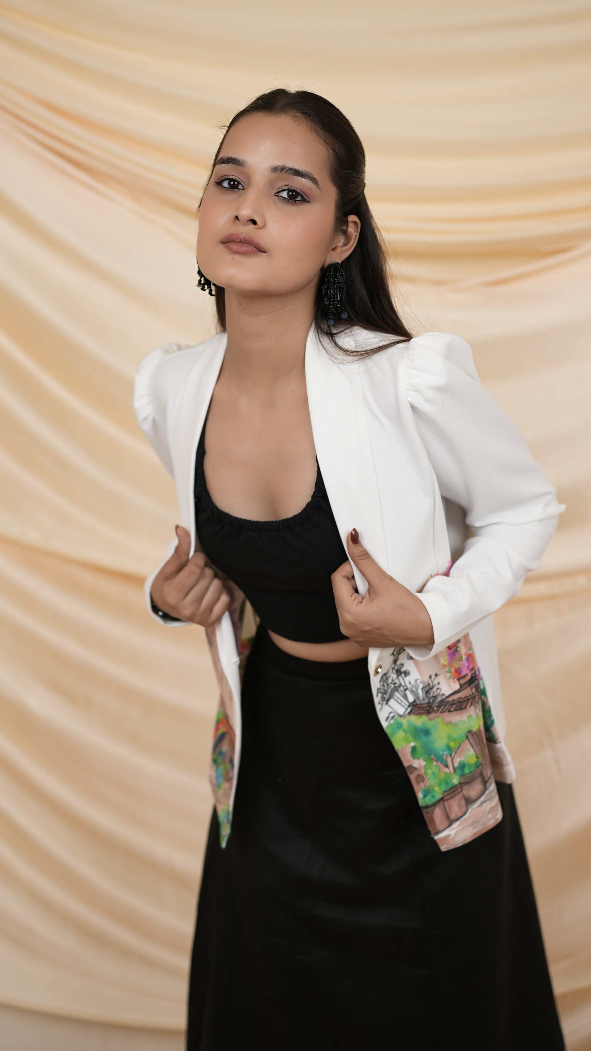 Women wearing a white blazer with a colorful hand painted design and black skirt.
