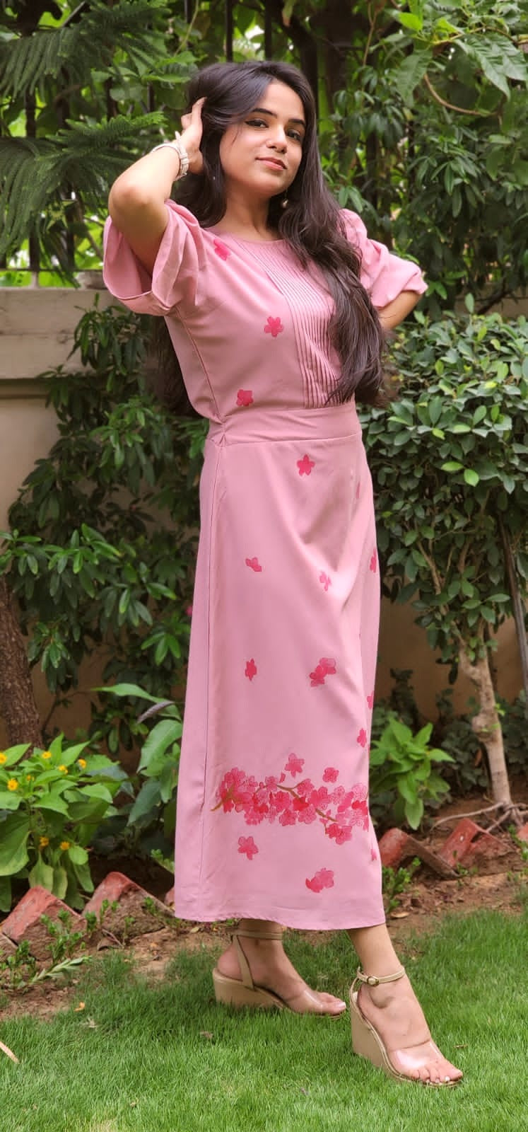 Woman wearing a pink dress with floral patterns in an outdoor setting