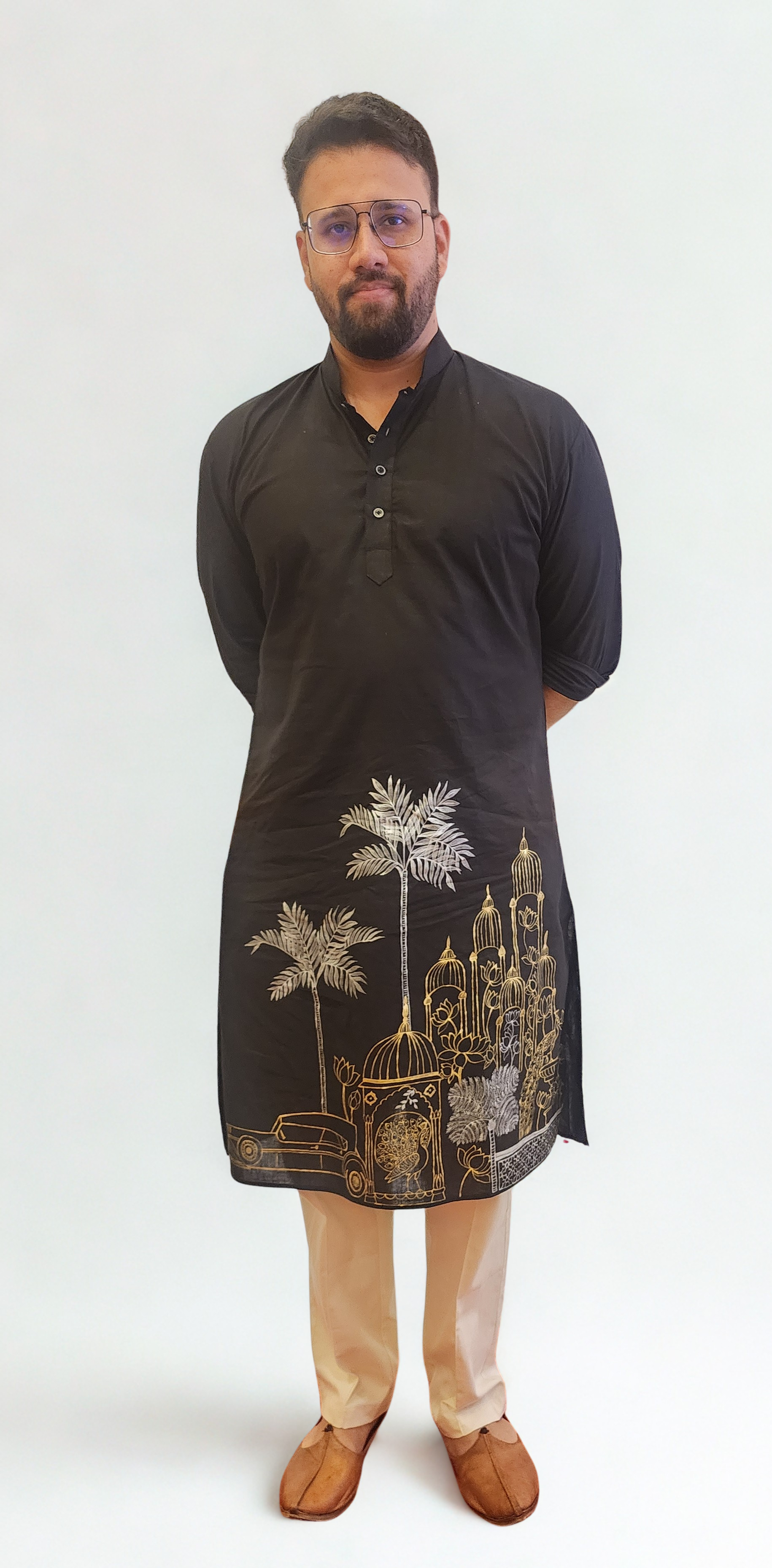 Man wearing a black embroidered kurta with white pants on a white background