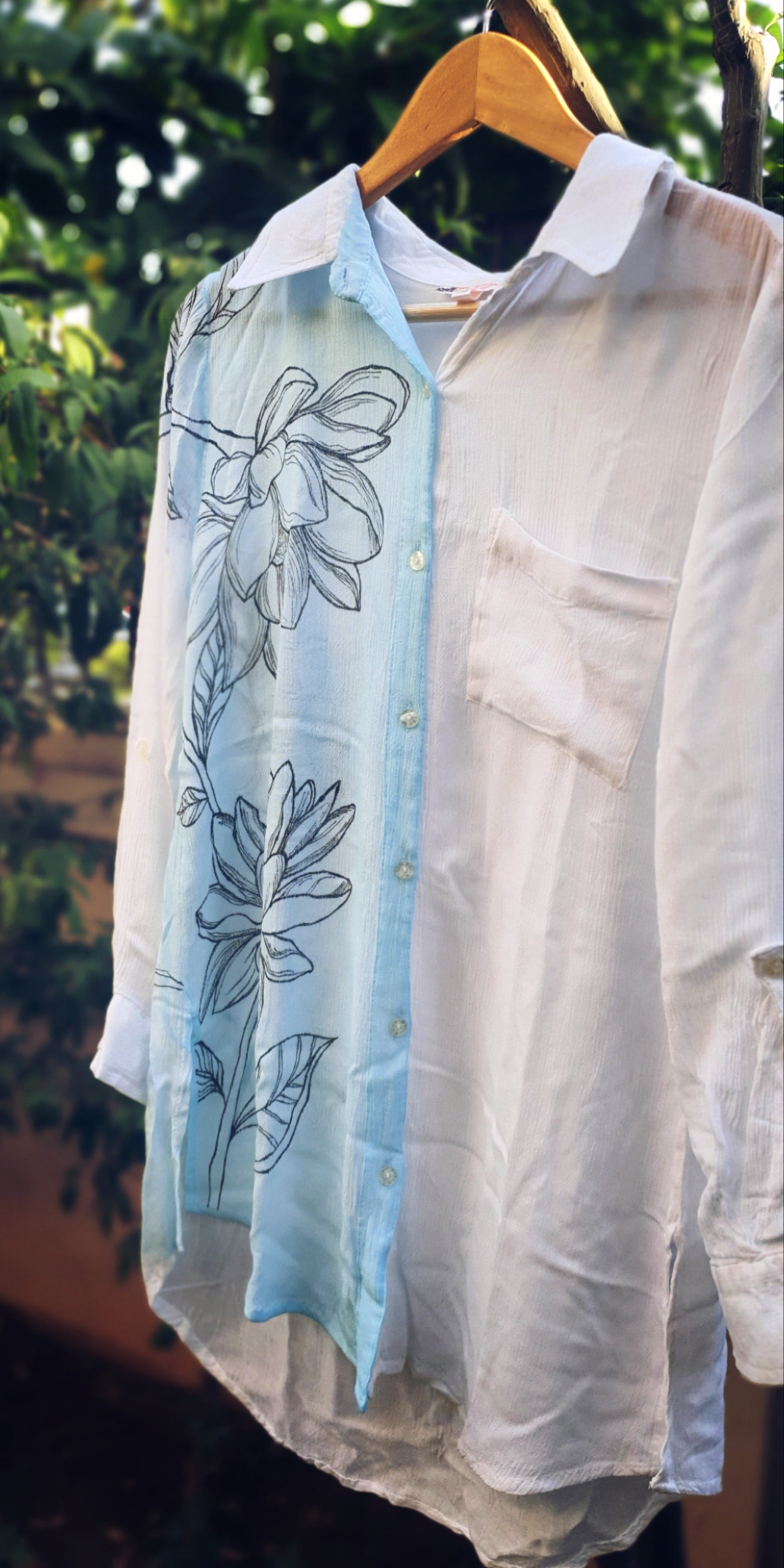 Light-colored shirt with floral shirt on a hanger against a natural background
