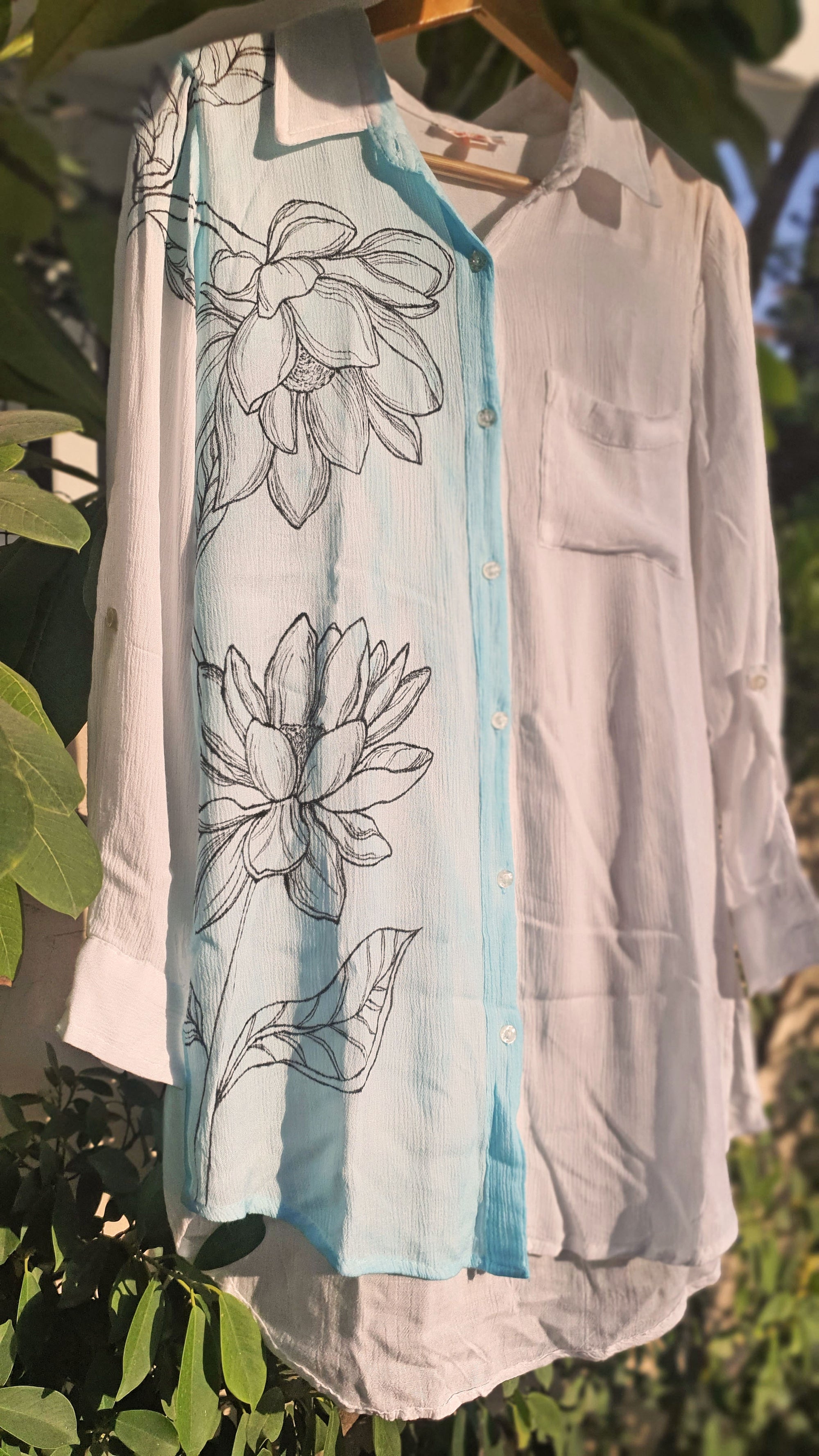 Light-colored shirt with floral shirt on a hanger against a natural background